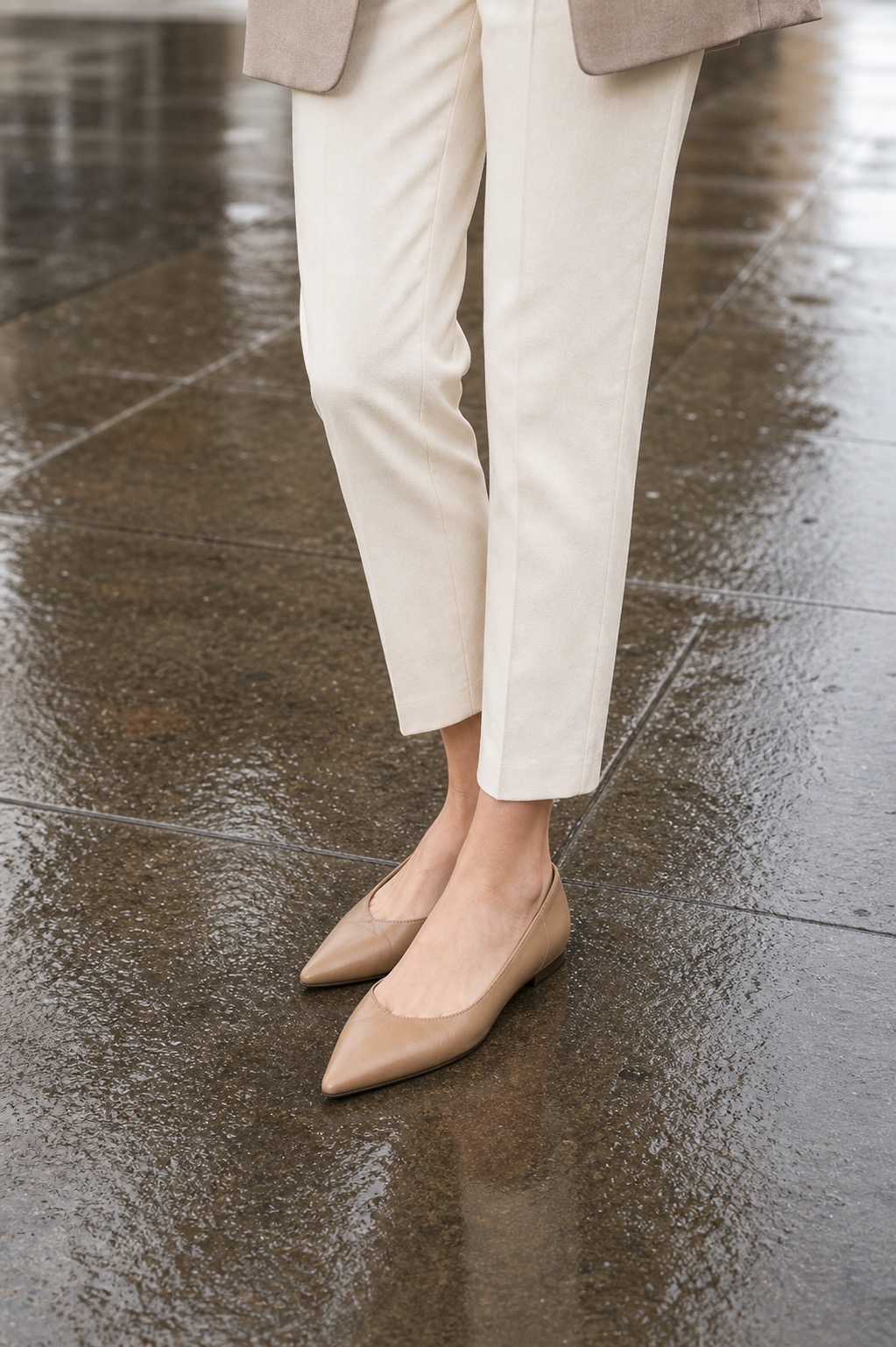 Spring Rain Outfit: a relaxed blazer, ankle pants, and pointed flats shoe and hem detail: Light taupe relaxed blazer, White knit tee, Cream ankle pants, Tan pointed flats, Structured neutral tote styling reference image
