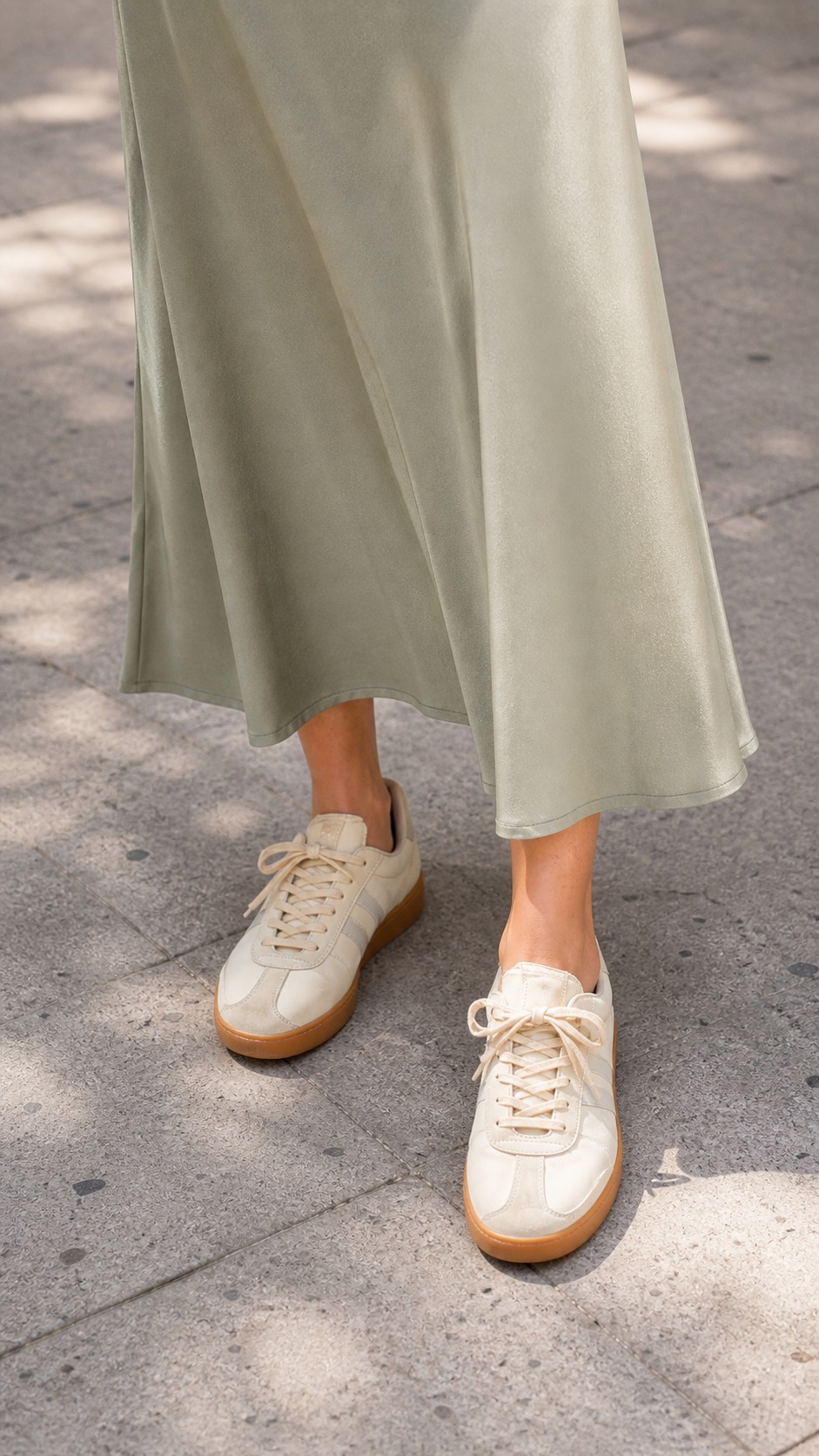 Spring Brunch Outfit: a denim jacket, slip skirt, and terrace sneakers shoe and hem detail: Medium-blue denim jacket, Black fitted short-sleeve knit, Sage satin slip skirt, Gum-sole terrace sneakers, Cream bucket shoulder bag styling reference image