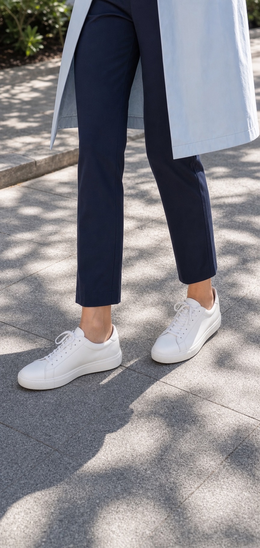 Spring Athleisure Outfit: a light coat, ankle pants, and sneakers shoe and hem detail: Sky-blue lightweight spring coat, White cotton tee, Navy straight ankle pants, Clean white leather sneakers, Oatmeal compact backpack styling reference image