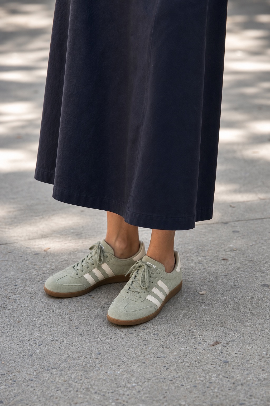 School Pickup Outfit: a zip polo, maxi skirt, and trainers shoe and hem detail: Ecru zip knit polo, Ink navy cotton maxi skirt, Sage green low trainers, Light gray crescent shoulder bag styling reference image